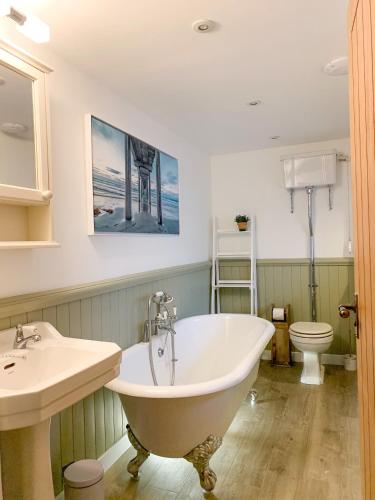 a bathroom with a tub and a sink and a toilet at Balloan Cottage Cowshed in Inverness