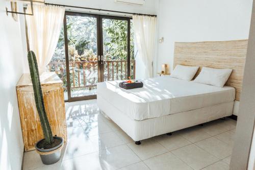 a bedroom with a large white bed and a cactus at Sultans Of Swell Uluwatu Bali in Uluwatu