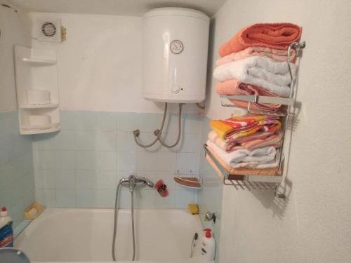 ein Badezimmer mit einer Badewanne und Handtüchern auf einem Regal in der Unterkunft Apartman Ana in Livno