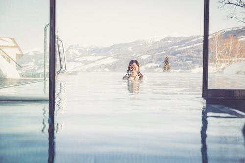 a woman is swimming in a pool of water at Hotel Annelies in Ramsau am Dachstein