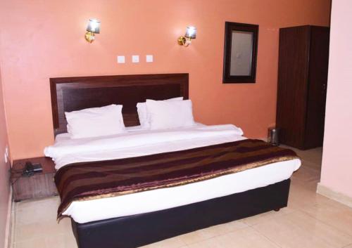 a bedroom with a large bed with orange walls at Residency Hotels Ogidi in Ogidi