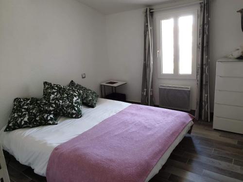Un dormitorio con una cama blanca con almohadas y una ventana en Ma Maison en Le Château-dʼOléron