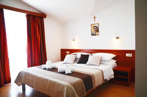 a bedroom with a large bed with a cross on the wall at Hotel Quattro Medjugorje in Međugorje