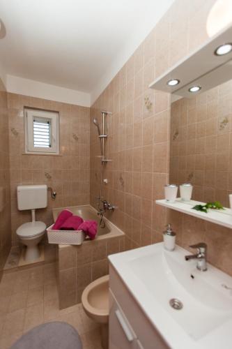 a bathroom with a sink toilet and a mirror at Villa Amica in Trogir