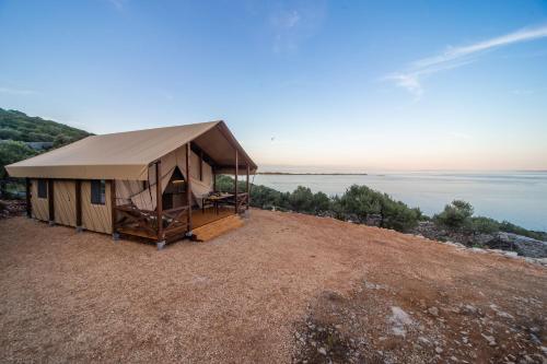 a tent on a beach near a body of water at Glamping Tents and Mobile Homes Trasorka in Veli Lošinj