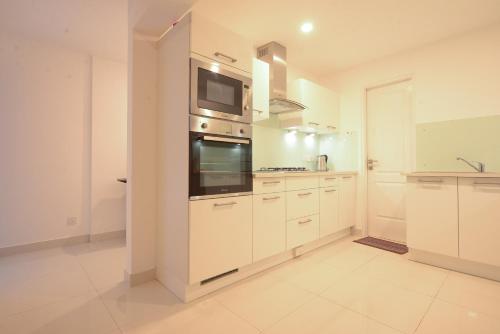 a large kitchen with white cabinets and a microwave at De Saram Residencies in Colombo