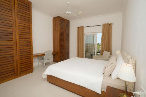a white bedroom with a bed and a window at De Saram Residencies in Colombo
