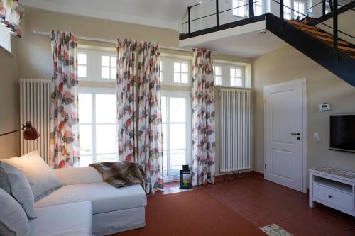 a living room with a white couch and windows at Lampenhäuschen in Dhronecken