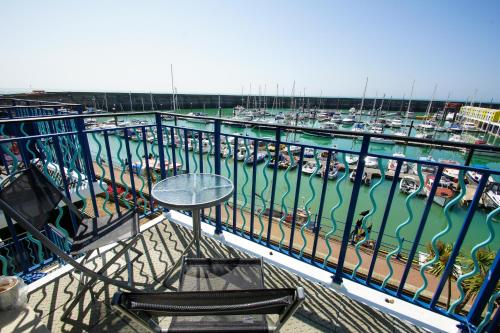 een tafel en stoelen op een balkon met een jachthaven bij Britannia Harbour View - Parking - by Brighton Holiday Lets in Brighton & Hove