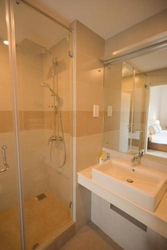 a bathroom with a sink and a shower with a mirror at De Saram Residencies in Colombo
