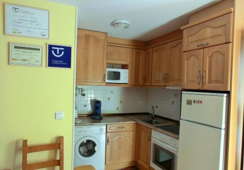 a kitchen with wooden cabinets and a white refrigerator at Casa A Ruata in Torla