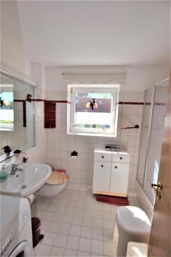 a bathroom with a sink and a toilet and a window at Sanddorn-Ostseering-4C in Hohwacht