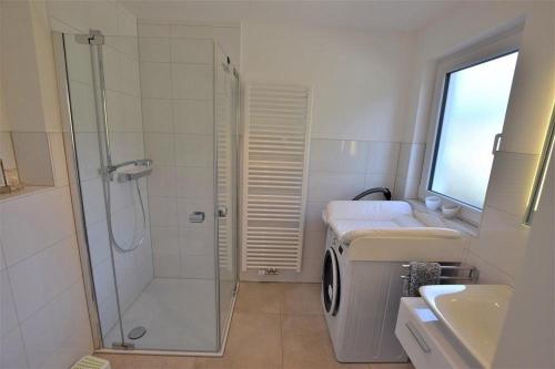 a bathroom with a shower and a sink and a washing machine at Nordlicht-Reiher-2-Appat-3 in Hohwacht