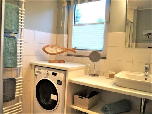 a bathroom with a washing machine and a sink at Sandkorn-H in Hohwacht