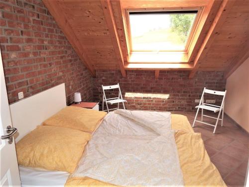 1 dormitorio con 1 cama con 2 sillas y una ventana en Ostseeliebe-Oben-Rechts-1-KK-H en Hohwacht