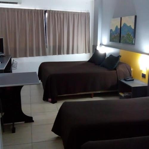 a hotel room with two beds and a desk at Apart Hotel Alvear in Rosario