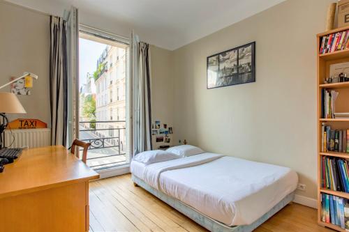 Schlafzimmer mit einem Bett, einem Schreibtisch und einem Fenster in der Unterkunft Veeve - Secluded in the Heart of the 16th in Paris