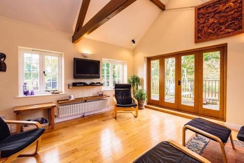 a living room with wooden floors and a flat screen tv at Mid-Wales Farmhouse, swimming pool, tranquil countryside views, sleeps 14 in Meifod