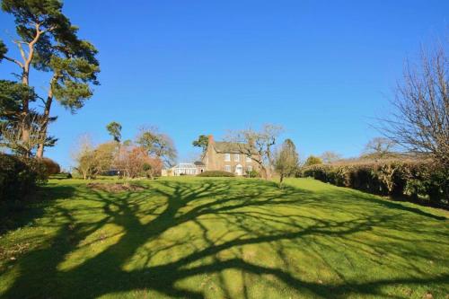 a large grassy yard with a house in the background at Mid-Wales Farmhouse, swimming pool, tranquil countryside views, sleeps 14 in Meifod