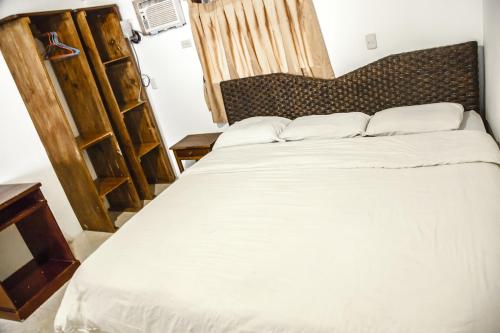 a bedroom with a large white bed with a wooden headboard at Casa del Sol in Montañita