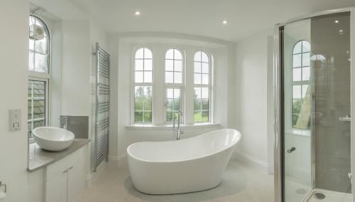 a white bathroom with a tub and a shower at Carlogie House in Carnoustie