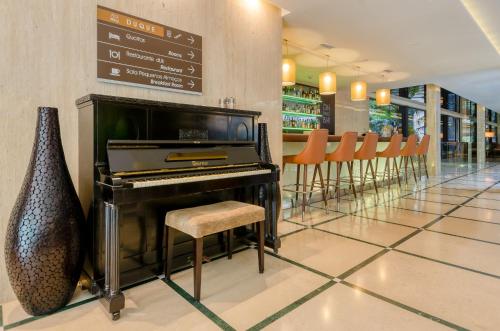 a piano in a restaurant with a bar with chairs at TURIM Av. Liberdade Hotel in Lisbon