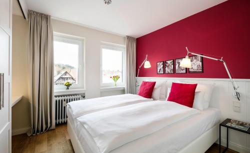 a bedroom with a large white bed with red walls at Residenz Seeterrasse Restaurant & Hotel in Wangen