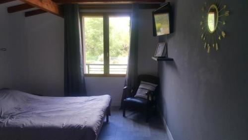 a bedroom with a bed and a chair and a window at Le Termenès in Félines-Termenès