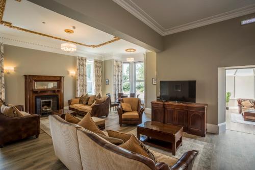 a living room with a couch and a tv and chairs at Carlogie House in Carnoustie