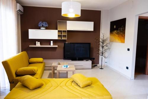 a living room with a yellow couch and a tv at ALMI B&B in Sarno