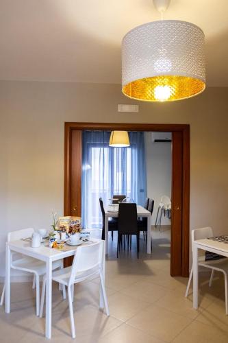 a dining room and living room with a white table and chairs at ALMI B&B in Sarno