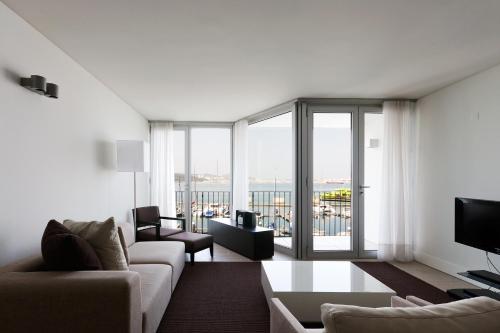 a living room with a couch and a large window at Troia Residences - Apartamentos Marina in Troia