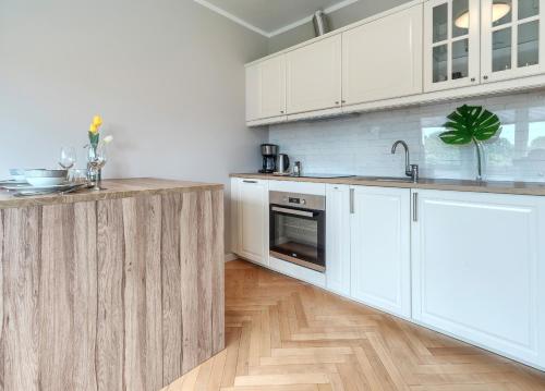 a kitchen with white cabinets and a wooden floor at Studio Mini Moris - ACCO RENT in Sopot
