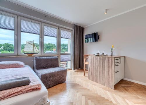a bedroom with a bed and a chair and windows at Studio Mini Moris - ACCO RENT in Sopot
