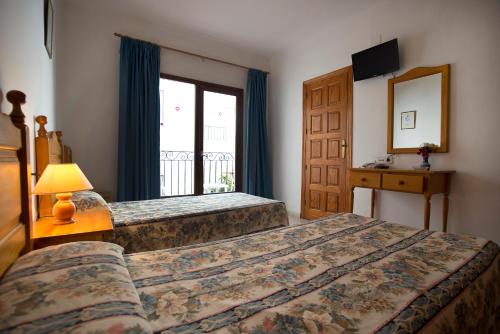 una camera d'albergo con due letti e una finestra di Hostal Sa Rota a Santa Eularia des Riu