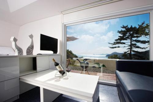 uma sala de estar com uma mesa branca e uma grande janela em Tropical Dream Spa Caravan em Geoje