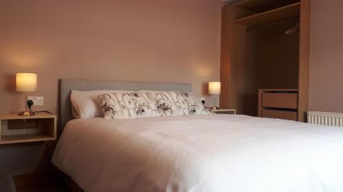 a bedroom with a large white bed with two lamps at Suzies Self Catering Belmont in Belmont