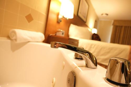 a bathroom with a sink and a bedroom with a bed at Rosslyn Inn & Suites in Edmonton