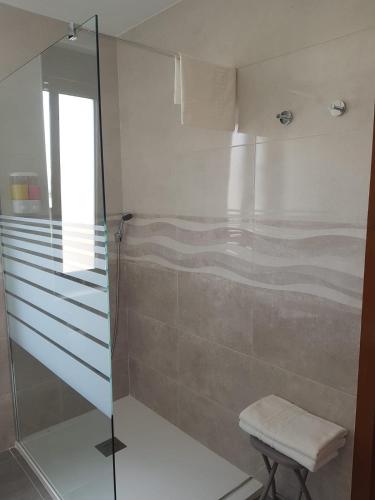 a bathroom with a glass shower with a stool at Hostería Carmen in Santillana del Mar
