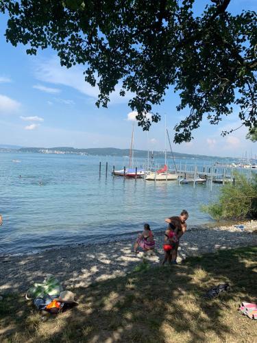 a group of people on a beach with boats in the water at FeWo Michaela Köst in Konstanz