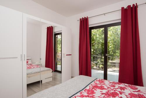 Schlafzimmer mit roten Vorhängen, einem Bett und einem Fenster in der Unterkunft Apartmani Jadranka in Vodice