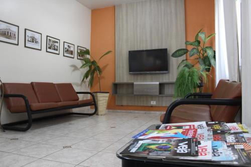 a living room with a couch and a tv at Limeira Plaza Hotel in Limeira