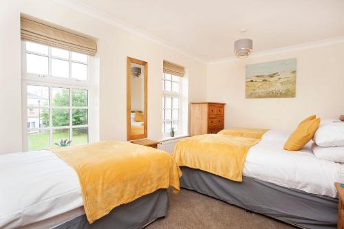 two beds in a bedroom with white walls and windows at Thomas, off Leeman Road, Sleeps 9 in York