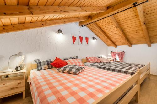 two beds in a room with wooden ceilings at House Pavincic in Lovran