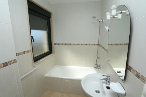 y baño blanco con lavabo y bañera. en viviendas de uso turístico FINISTERRAE PLAYA, en Finisterre