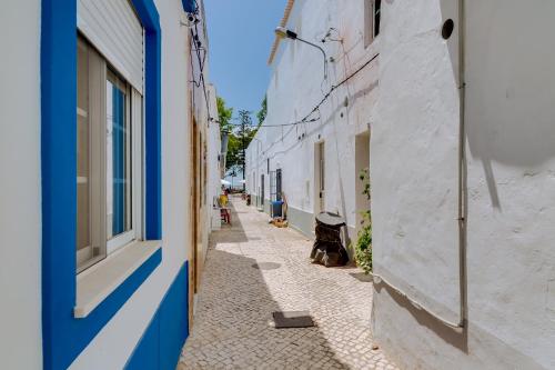 a narrow alley with blue and white buildings at Casa do Chico in Olhão