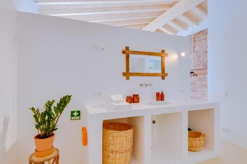 a white bathroom with a sink and a mirror at Casa do Chico in Olhão