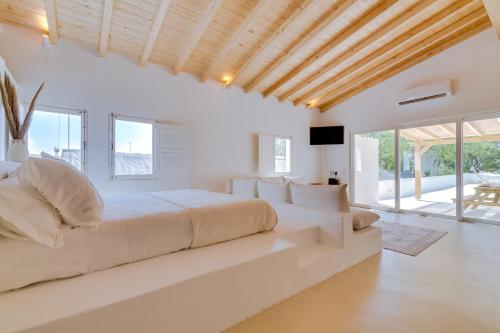 a white bedroom with a large bed and windows at Casa do Chico in Olhão