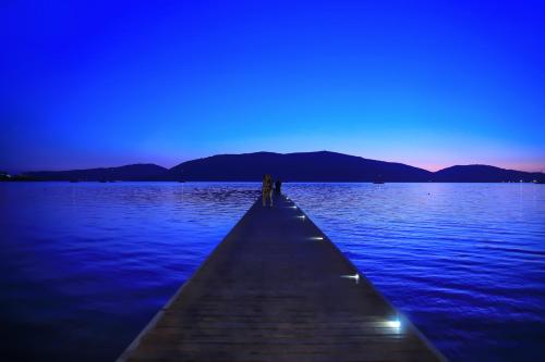 two people standing on a pier over water at night at Hotel Corte Rosada in Porto Conte