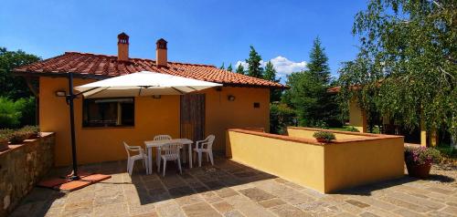a yellow house with an umbrella and a table and chairs at Torrebianca Tuscany in Rignano sullʼArno